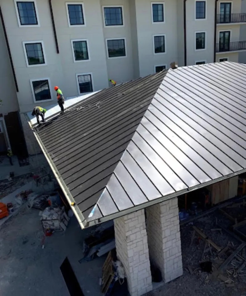 Crew installing standing seam metal roof panels on a commercial project in Red Bluff